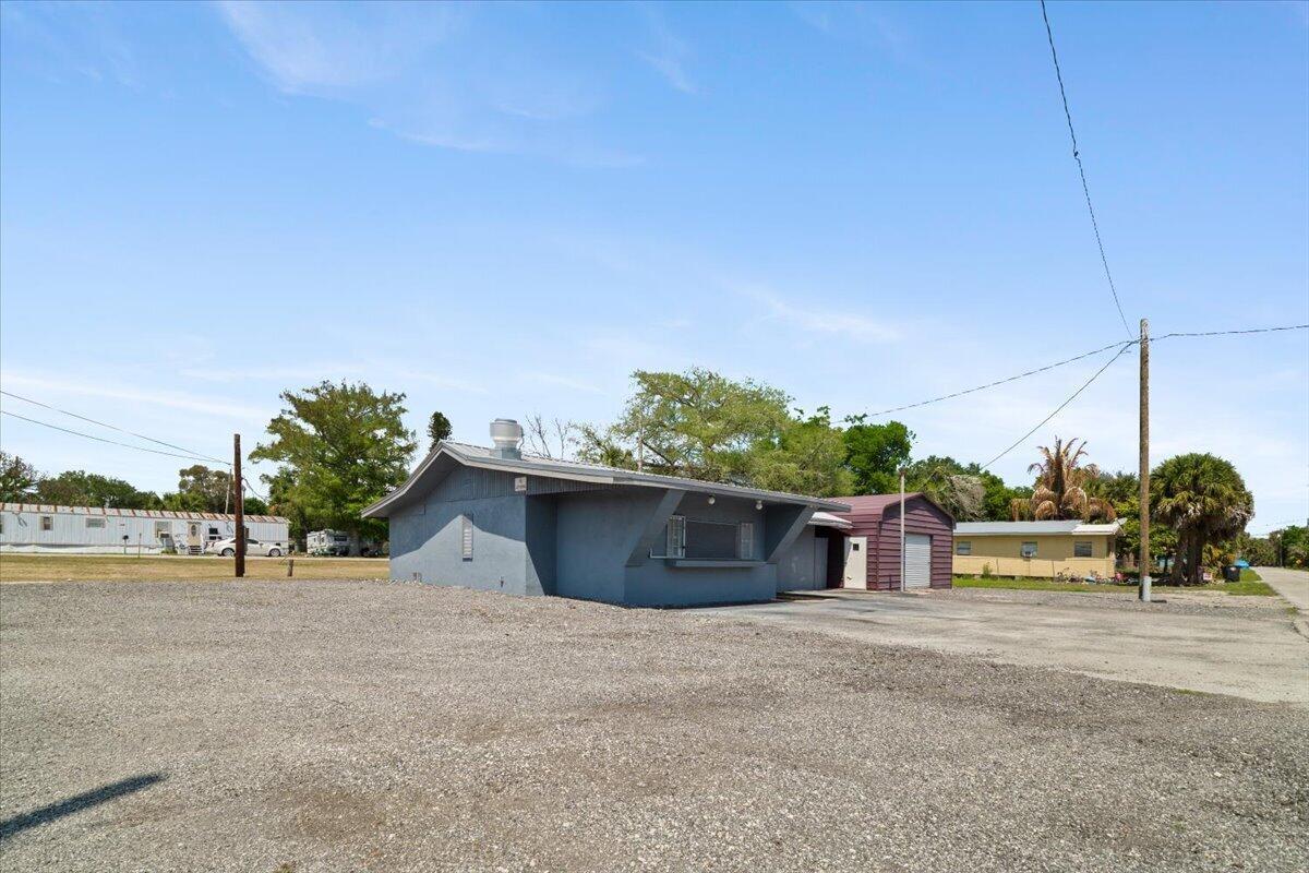 A gray single-story building sits on a large gravel lot under a clear blue sky — 1023 Lee Street, Moore Haven FL 33471, MOORE HAVEN, FL