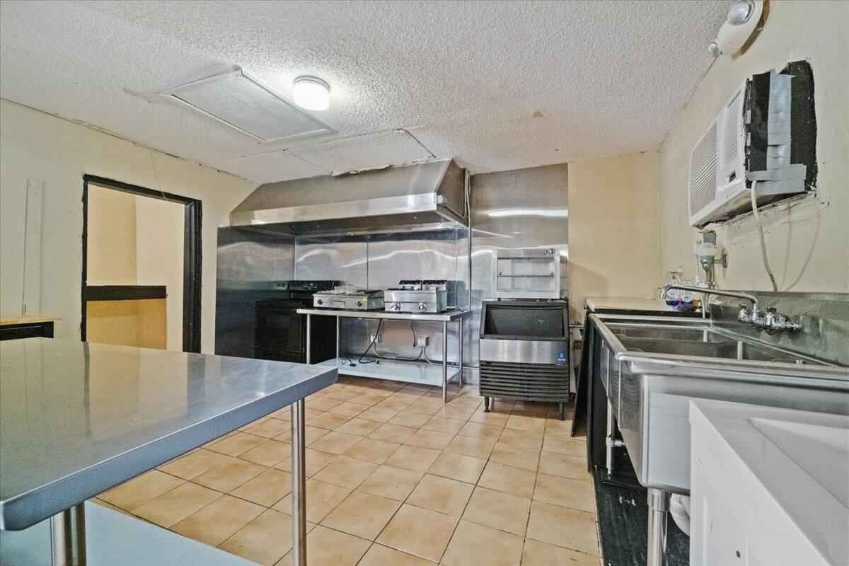 A commercial kitchen featuring stainless steel appliances, a metal hood, and tiled flooring — 1023 Lee Street, Moore Haven FL 33471, MOORE HAVEN, FL