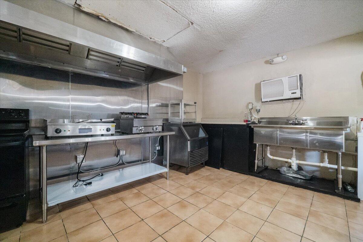 A commercial kitchen features stainless steel appliances, a vent hood, a sink, and tiled flooring — 1023 Lee Street, Moore Haven FL 33471, MOORE HAVEN, FL