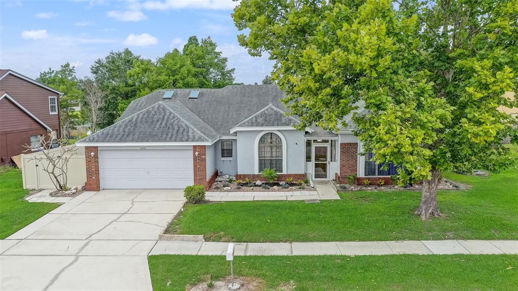A single-story house with a two-car garage, gray siding, brick accents, and a large tree — 2358 OLDFIELD DRIVE, ORLANDO, FL