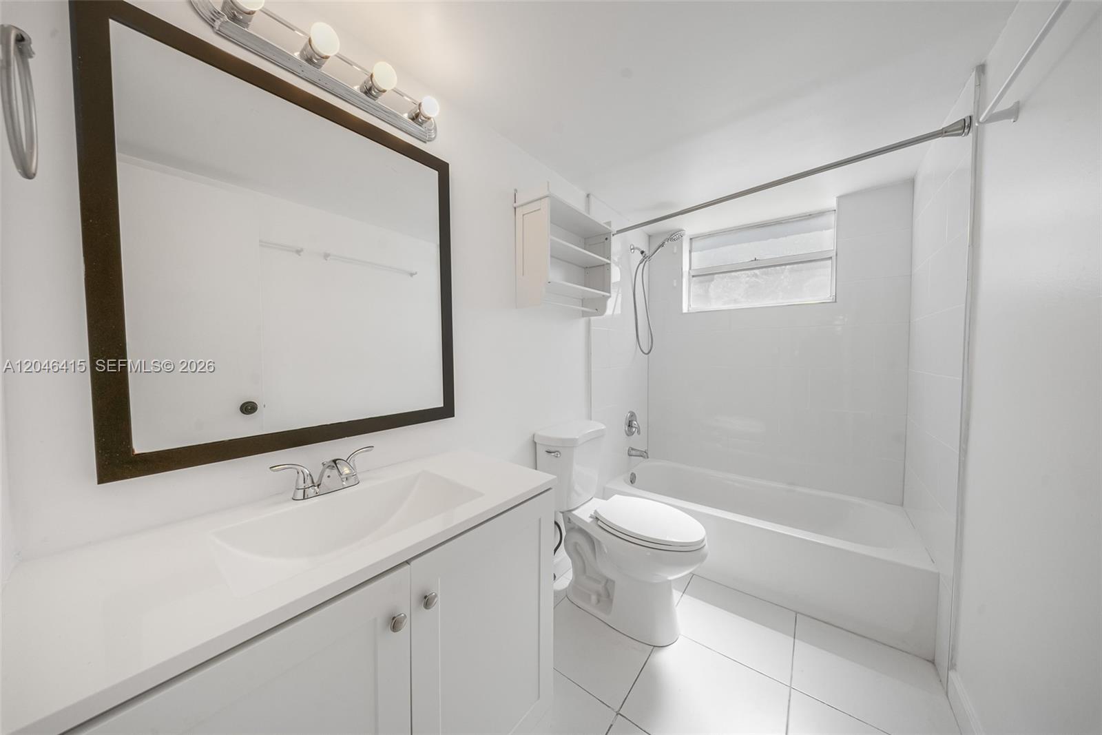 A white bathroom features a vanity with a dark-framed mirror, toilet, and shower-tub combo — 14155 SW 87th St, Miami FL 33183, MIAMI, FL