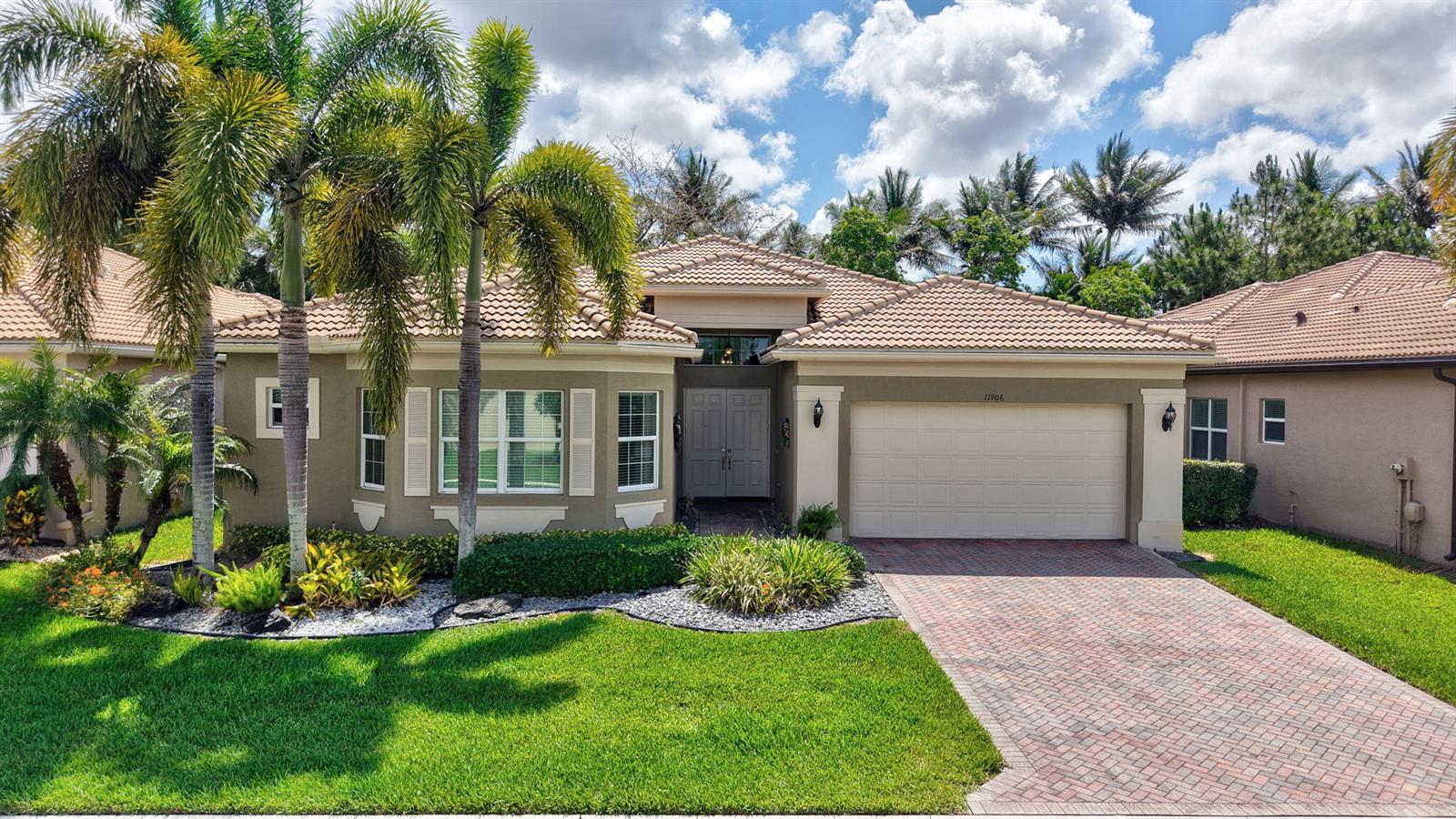 A single-story house with a beige stucco exterior, tiled roof, and a brick paver driveway — 11906 Catskill Commons Lane, Boynton Beach FL 33473, BOYNTON BEACH, FL