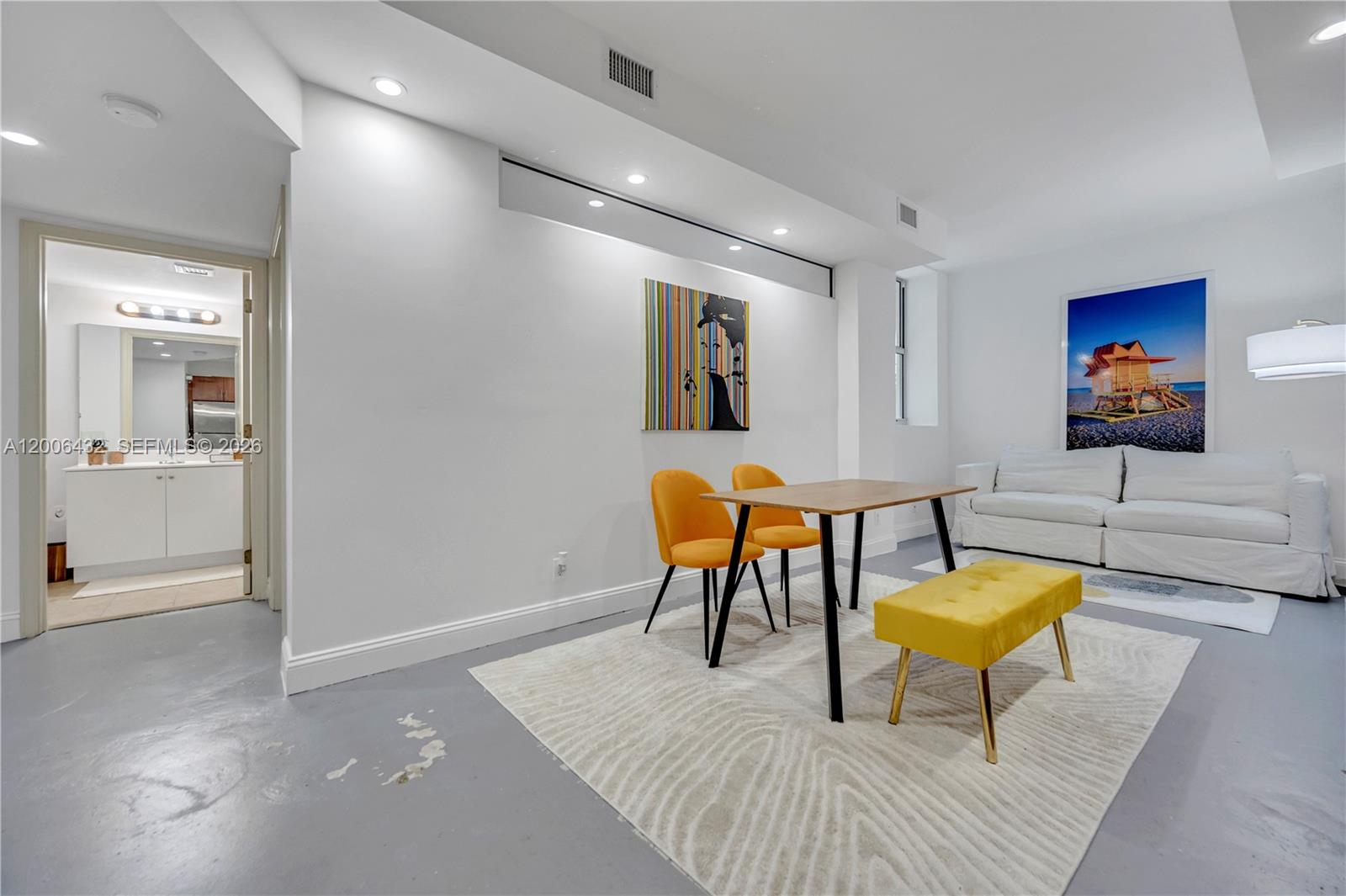 A dining area with orange chairs and a yellow bench sits beside a white sofa — 111 E Flagler St # 506, Miami FL 33131, MIAMI, FL