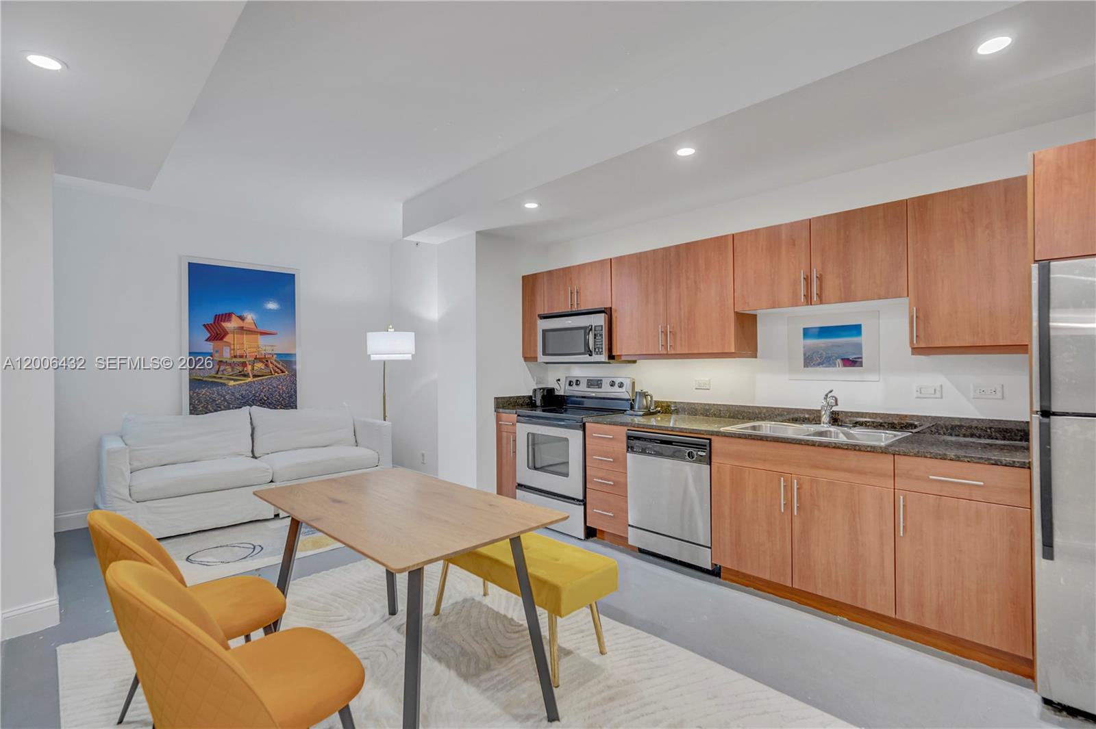 A kitchen and dining area features wood cabinets, stainless steel appliances, and yellow seating — 111 E Flagler St # 506, Miami FL 33131, MIAMI, FL