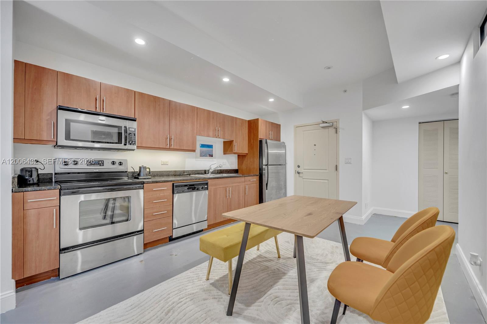 A kitchen features wood cabinets, stainless steel appliances, and a dining area with a rug — 111 E Flagler St # 506, Miami FL 33131, MIAMI, FL