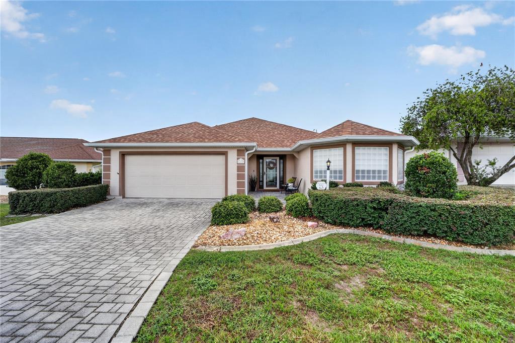 A single-story house with a paved driveway, two-car garage, and a landscaped front yard — 11193 SE 173RD PLACE, SUMMERFIELD, FL