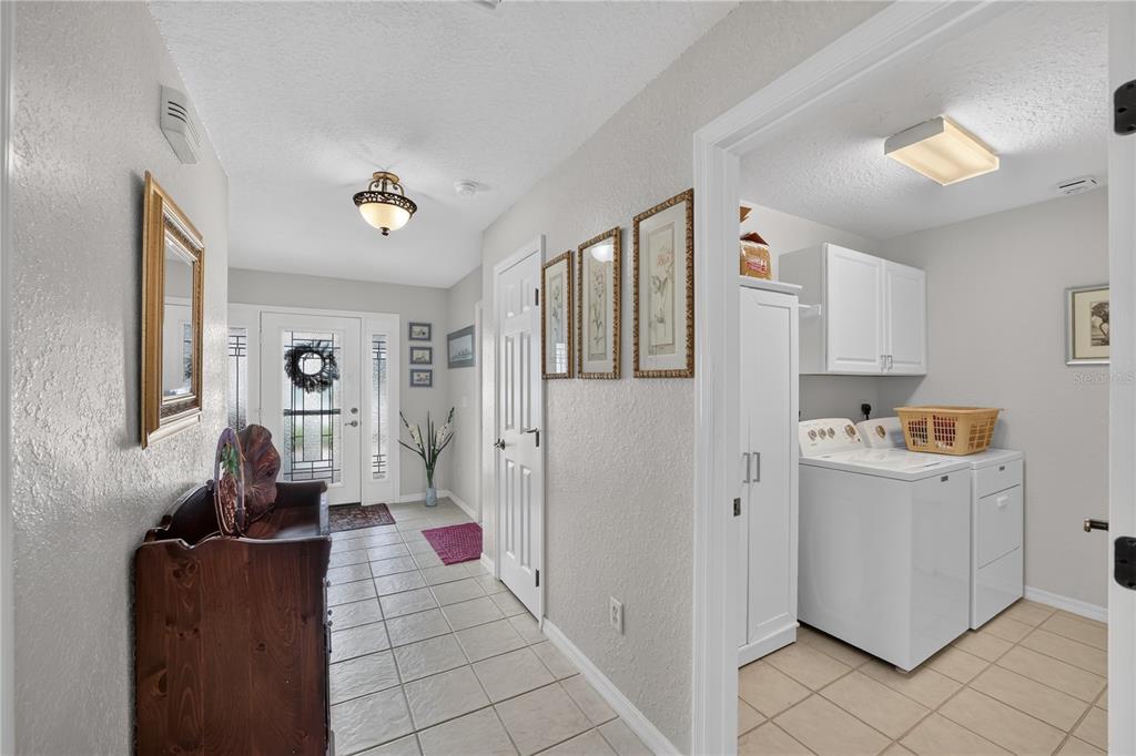 A tiled entryway leads to a front door and an adjacent laundry room with white cabinets — 11193 SE 173RD PLACE, SUMMERFIELD, FL
