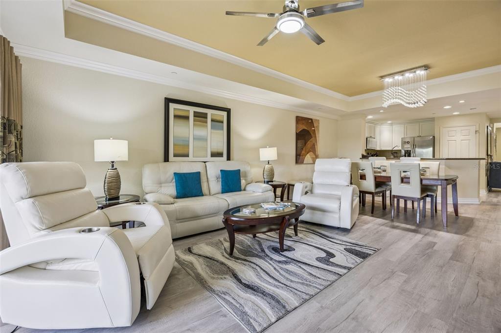 A living room with white leather furniture, a patterned rug, and an open kitchen area — 7602 SANDY RIDGE DR UNIT 103, REUNION, FL