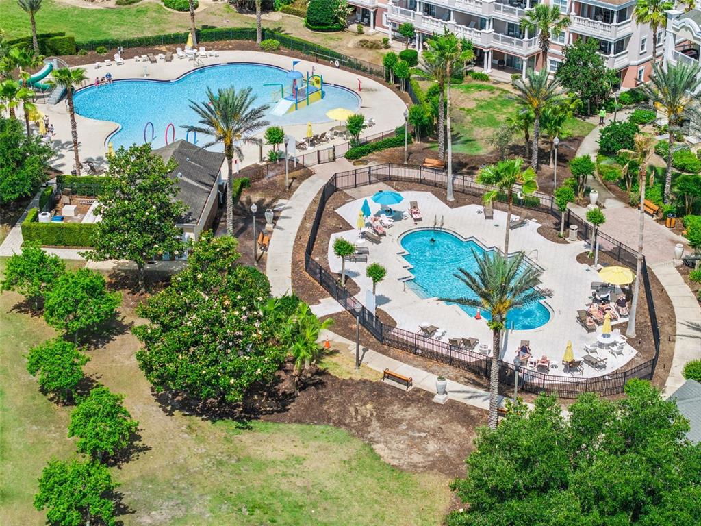 An aerial view shows two swimming pools, palm trees, and a multi-story residential building — 7602 SANDY RIDGE DR UNIT 103, REUNION, FL