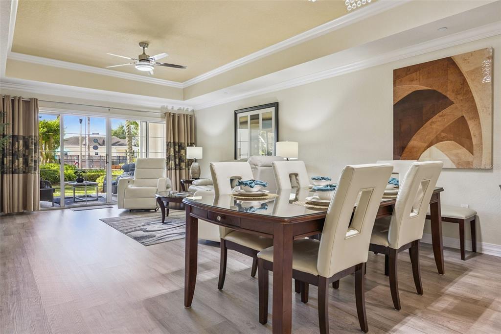 A dining area with a glass-topped table and chairs opens into a living room space — 7602 SANDY RIDGE DR UNIT 103, REUNION, FL