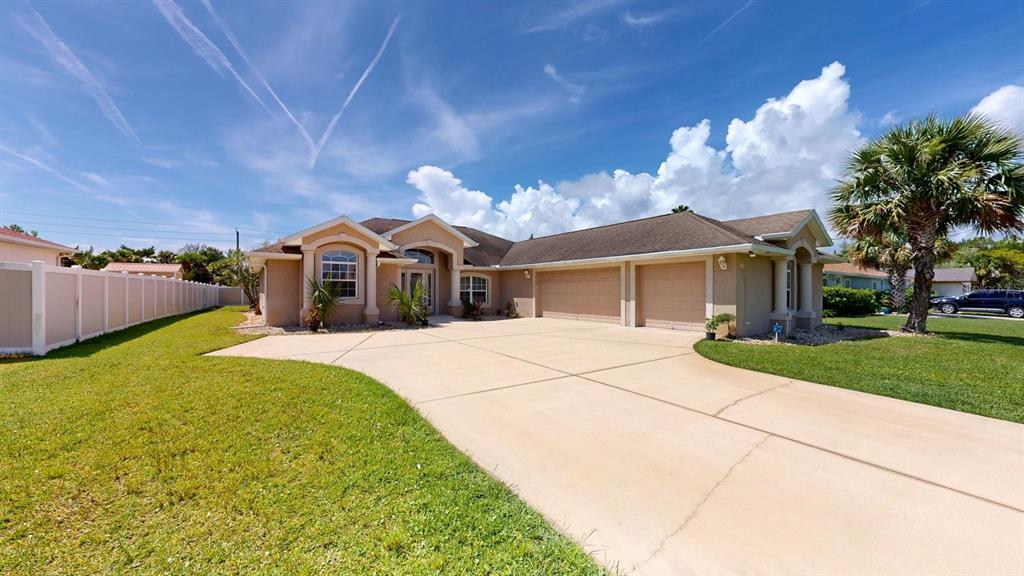 A single-story house with a large concrete driveway, three-car garage, and a palm tree — 40 COLLINGWOOD LANE, PALM COAST, FL