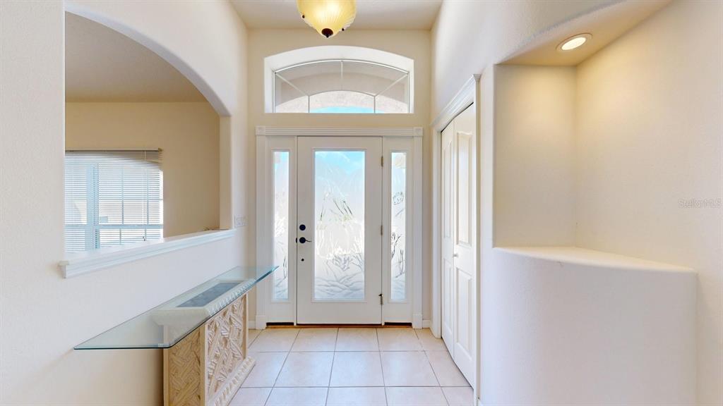 A bright entryway features a glass console table, tiled floors, and a decorative front door — 40 COLLINGWOOD LANE, PALM COAST, FL
