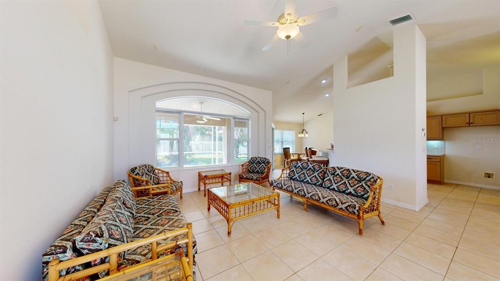 A living room with tile flooring, rattan furniture, and an arched window overlooking a patio — 40 COLLINGWOOD LANE, PALM COAST, FL