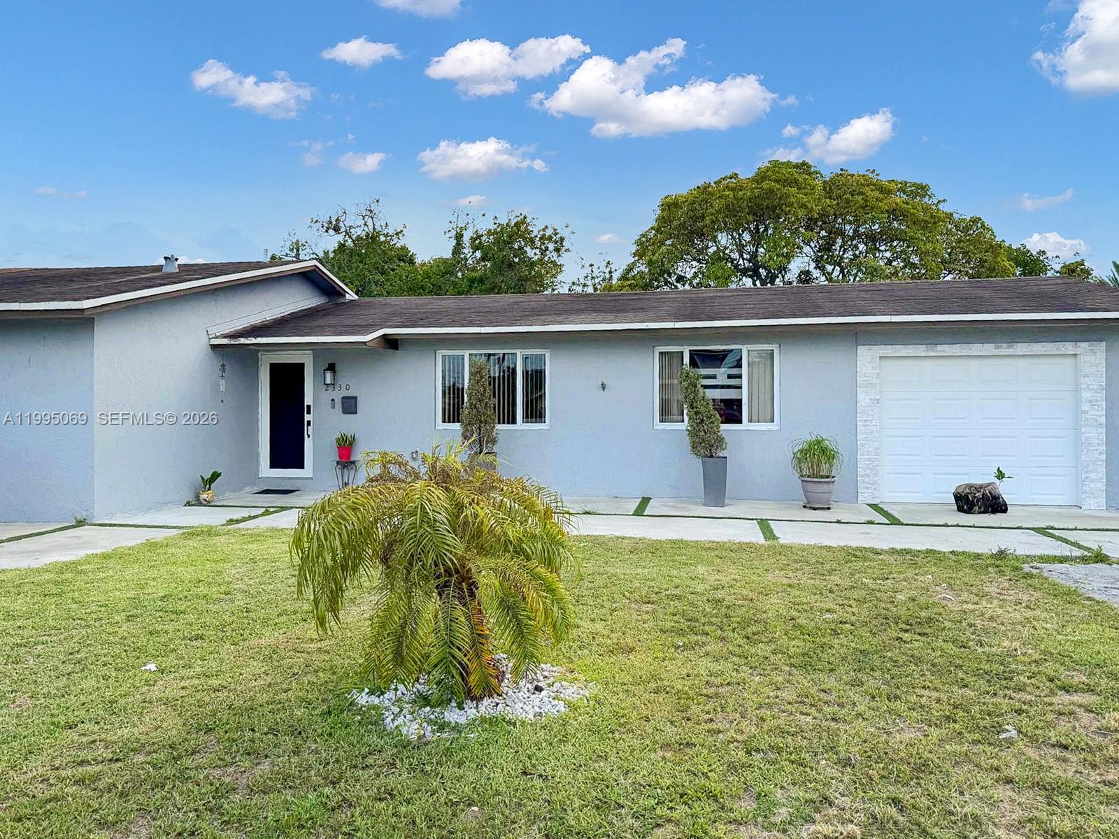 A single-story house with a light gray exterior, a white garage door, and a front lawn — 2330 W 6th Ct, Hialeah FL 33010, HIALEAH, FL