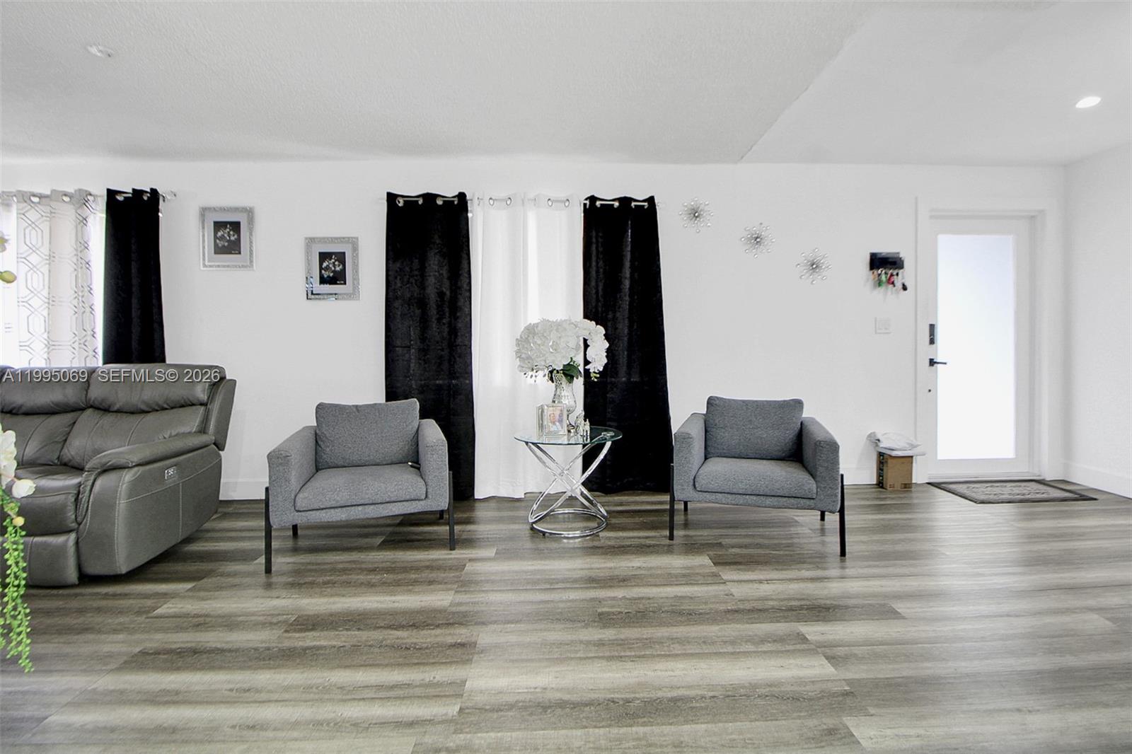 A living room features gray armchairs, a glass side table, and wood-look flooring — 2330 W 6th Ct, Hialeah FL 33010, HIALEAH, FL