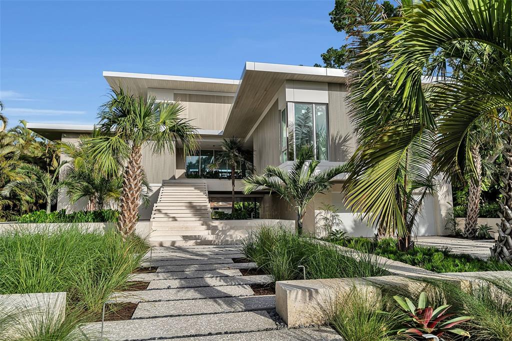A modern two-story house features a stone staircase, a paved walkway, and surrounding palm trees — 500 HARBOR COVE CIRCLE, LONGBOAT KEY, FL