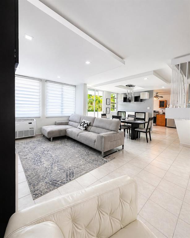 A living room with a gray sectional sofa, area rug, and an adjacent dining area — Ave. San Ignacio PRADOS DEL MONTE, GUAYNABO, PR