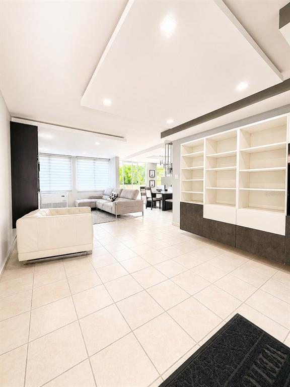 An open-concept living room features light tile flooring, a white sofa, and built-in shelving — Ave. San Ignacio PRADOS DEL MONTE, GUAYNABO, PR