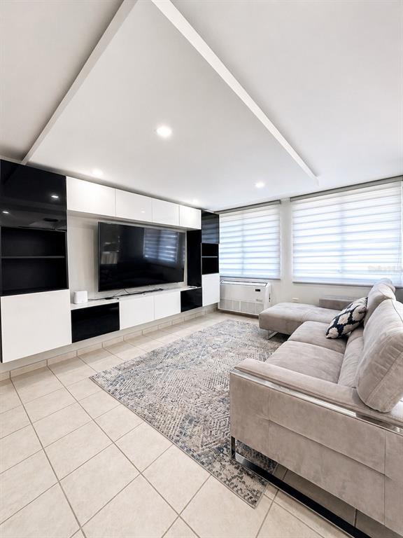 A living room features a large media wall, light tile floors, and a sectional sofa — Ave. San Ignacio PRADOS DEL MONTE, GUAYNABO, PR