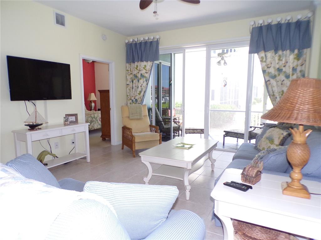 A living room features light tile floors, a white coffee table, and sliding glass doors — 1431 AQUI ESTA DRIVE UNIT 411, PUNTA GORDA, FL