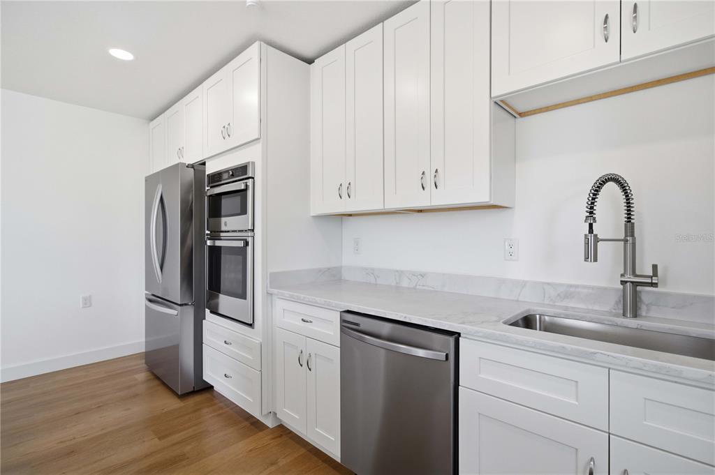 A modern kitchen features white cabinets, stainless steel appliances, and marble-look countertops — 765 JOHN RINGLING BOULEVARD UNIT 1CLARI, SARASOTA, FL