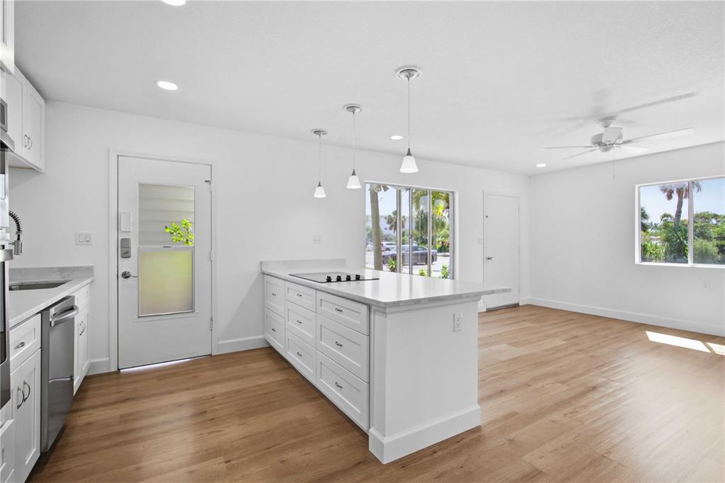 A bright kitchen features white cabinets, a central island with a cooktop, and wood flooring — 765 JOHN RINGLING BOULEVARD UNIT 1CLARI, SARASOTA, FL