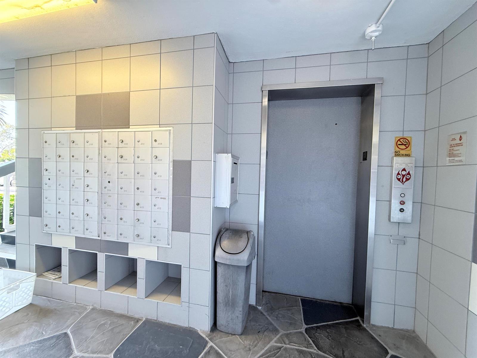 A lobby area features a wall of mailboxes, an elevator, and a trash bin — 4108 Oakridge V # 4108, Deerfield Beach FL 33442, DEERFIELD BEACH, FL