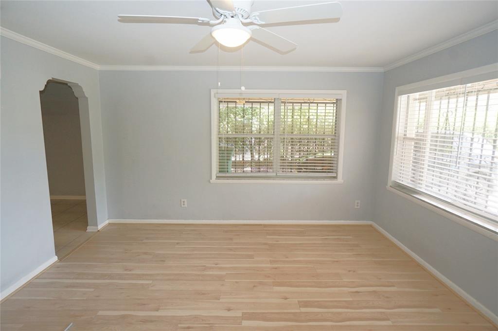 An empty room with light wood flooring, pale blue walls, and two windows with blinds — 207 N GOMEZ AVENUE, TAMPA, FL