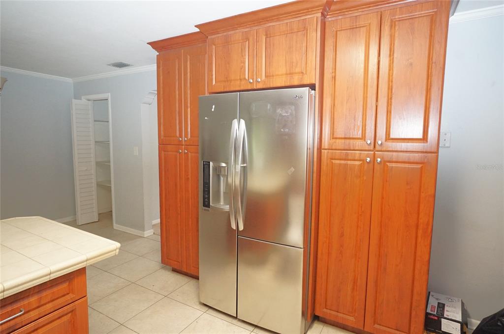 A stainless steel refrigerator is surrounded by wood cabinetry in a kitchen with tiled floors — 207 N GOMEZ AVENUE, TAMPA, FL