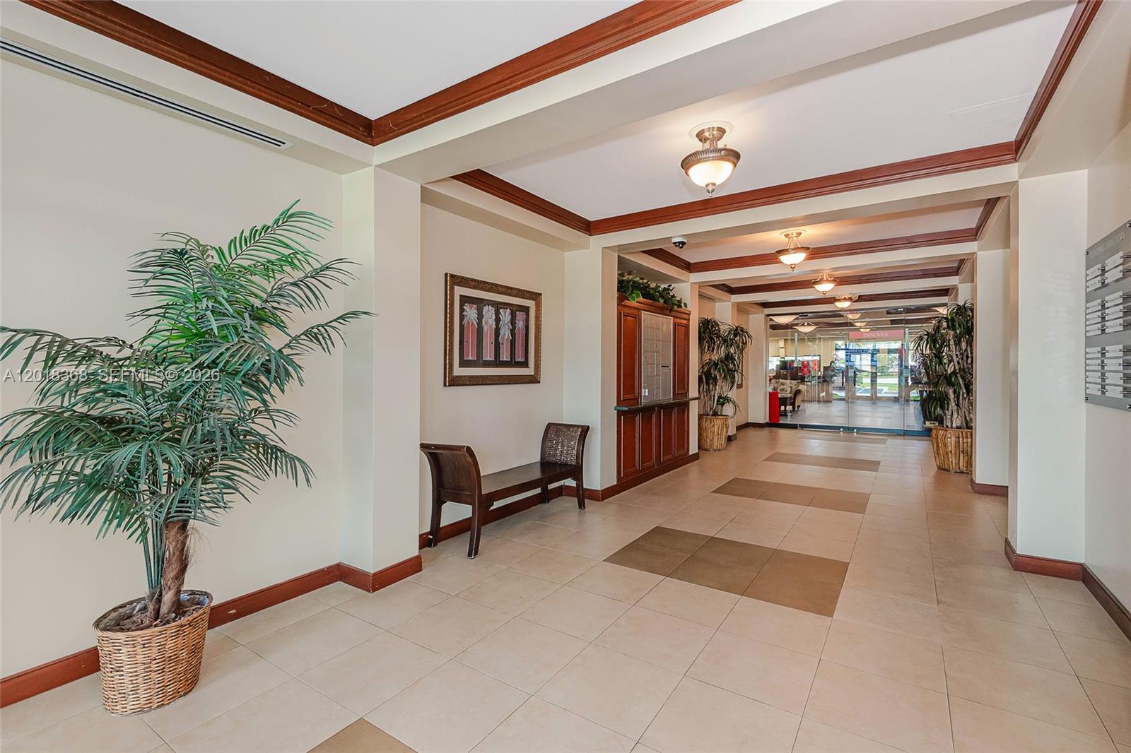 A lobby features a potted palm, a wooden bench, mailboxes, and tiled flooring — 5599 S University Dr # 205, Davie FL 33328, DAVIE, FL