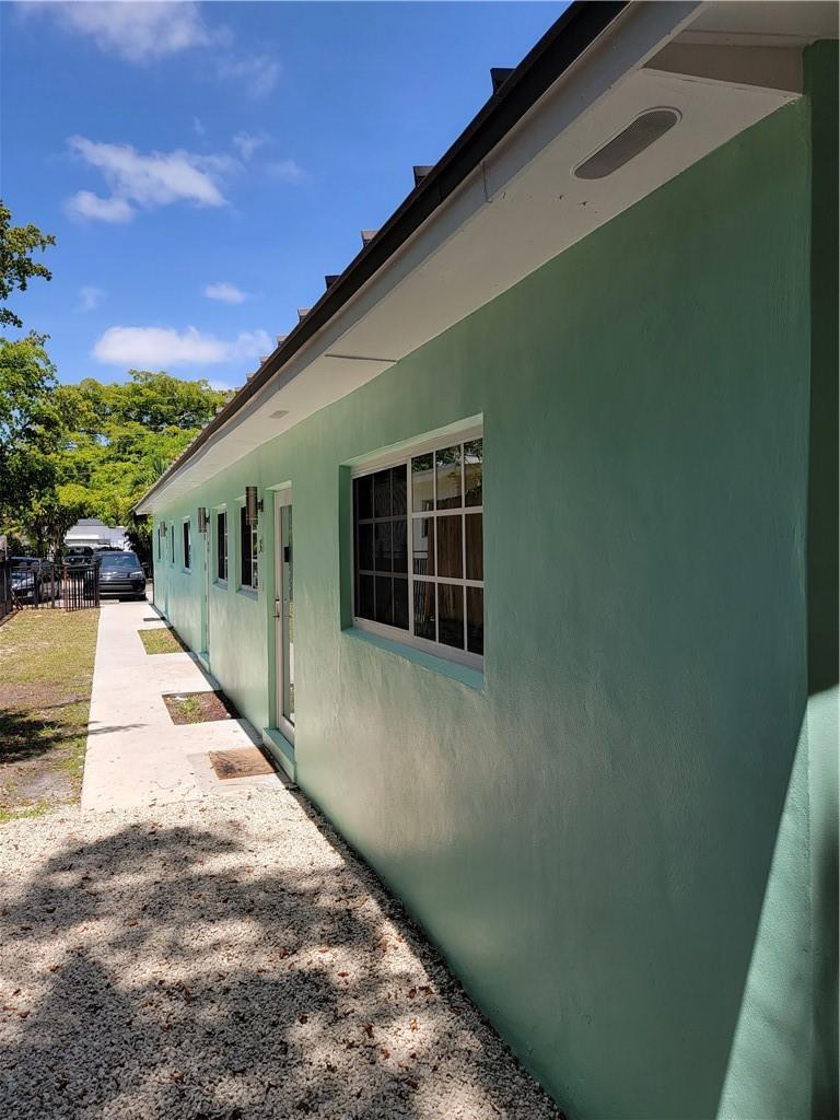 A side view of a light green stucco building with a gravel path and walkway — 1010 NW 3rd Avenue, Hallandale Beach FL 33009, HALLANDALE BEACH, FL