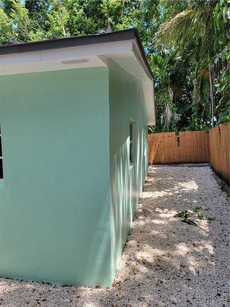 A side view of a light green house exterior with a gravel yard and fence — 1010 NW 3rd Avenue, Hallandale Beach FL 33009, HALLANDALE BEACH, FL