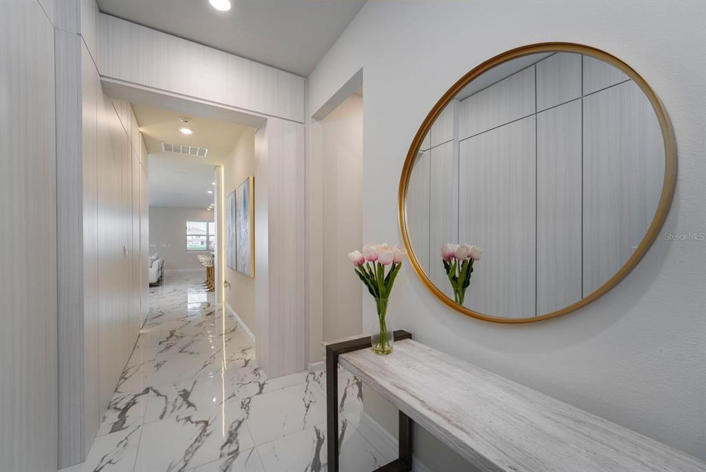 A modern hallway features white marble flooring, a round gold-framed mirror, and a console table — 13864 DESTIN BEACH LANE, ORLANDO, FL
