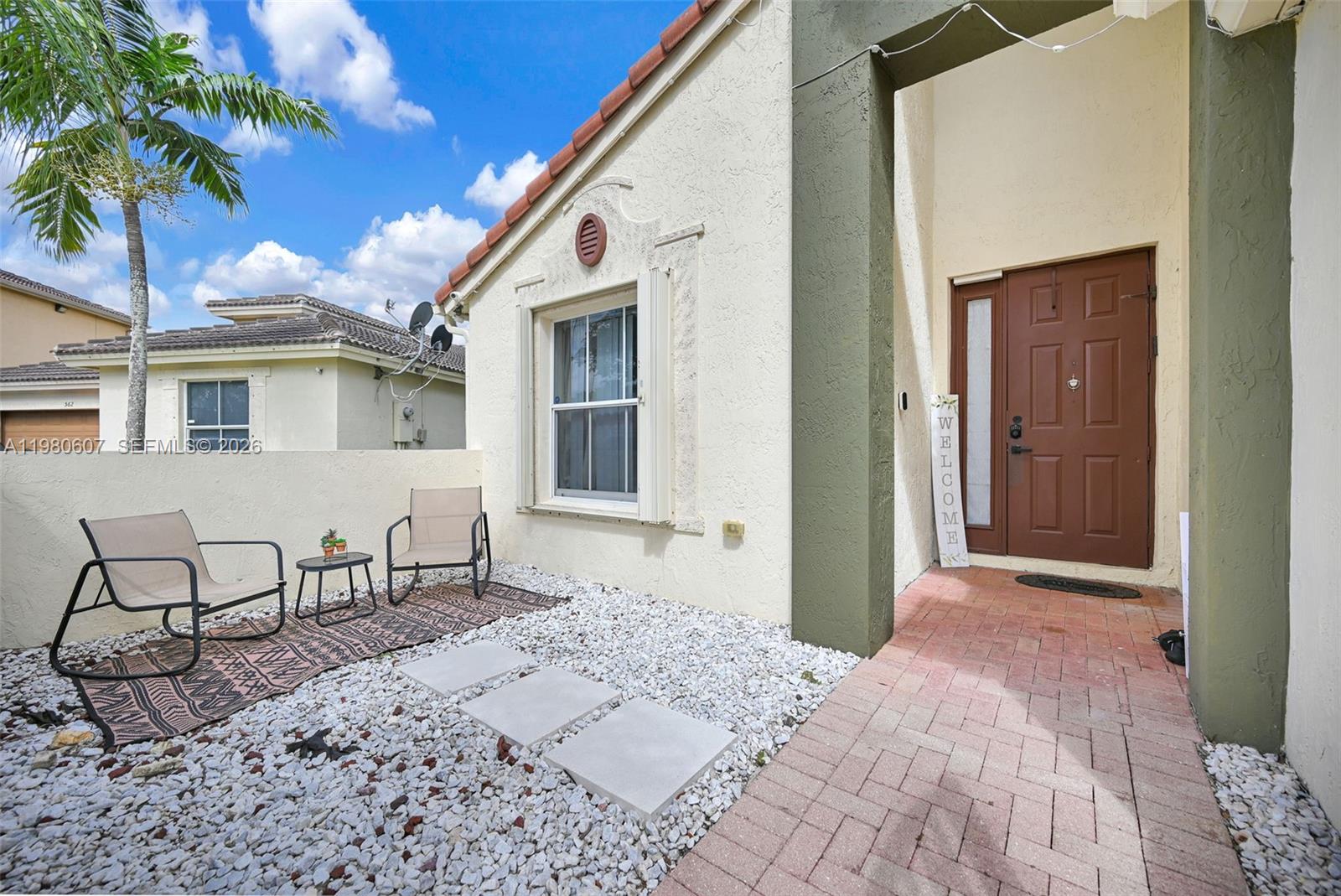 The exterior of a two-story house features a brick driveway, garage, and a small balcony — 2007 NE 6th Ct, Homestead FL 33033, HOMESTEAD, FL