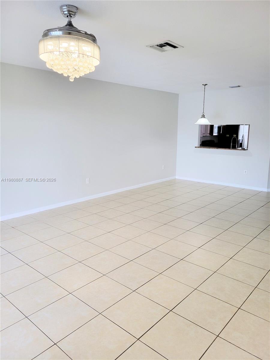 This room features light-colored tile flooring, a crystal chandelier ceiling fan, and a kitchen pass-through — 8263 SW 27th St # 102, Miramar FL 33025, MIRAMAR, FL