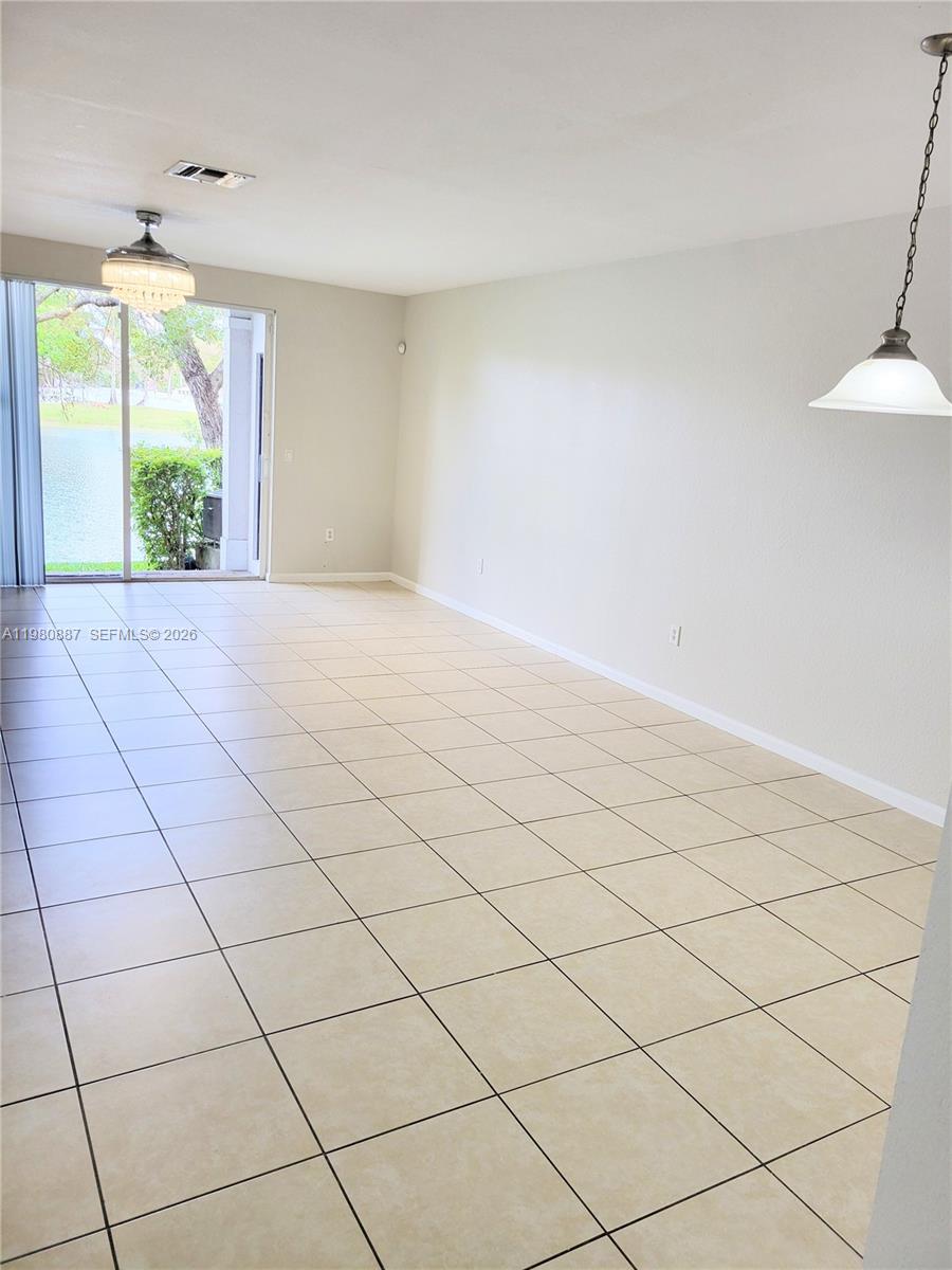 An empty room features light-colored tile flooring, a ceiling fan, and sliding glass doors — 8263 SW 27th St # 102, Miramar FL 33025, MIRAMAR, FL