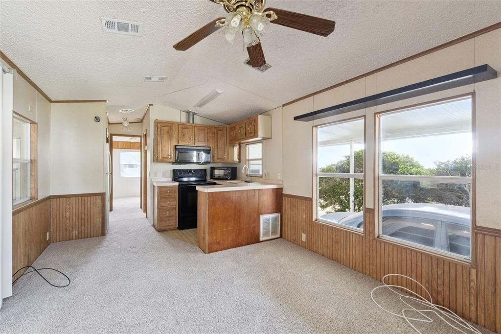 A kitchen with wood cabinets and a breakfast bar opens into a carpeted living area — 50989 HIGHWAY 27 UNIT 21, DAVENPORT, FL