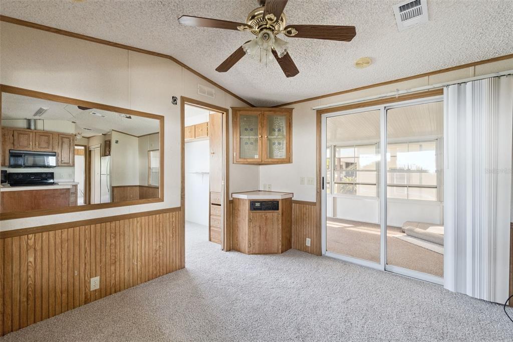 A carpeted room features wood wainscoting, a ceiling fan, a corner cabinet, and sliding glass doors — 50989 HIGHWAY 27 UNIT 21, DAVENPORT, FL