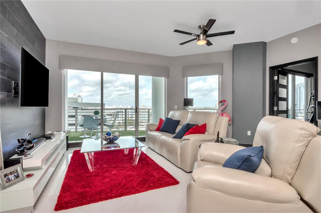 A modern living room features white leather furniture, a red rug, and a glass balcony door — 449 S 12TH STREET UNIT 1006, TAMPA, FL