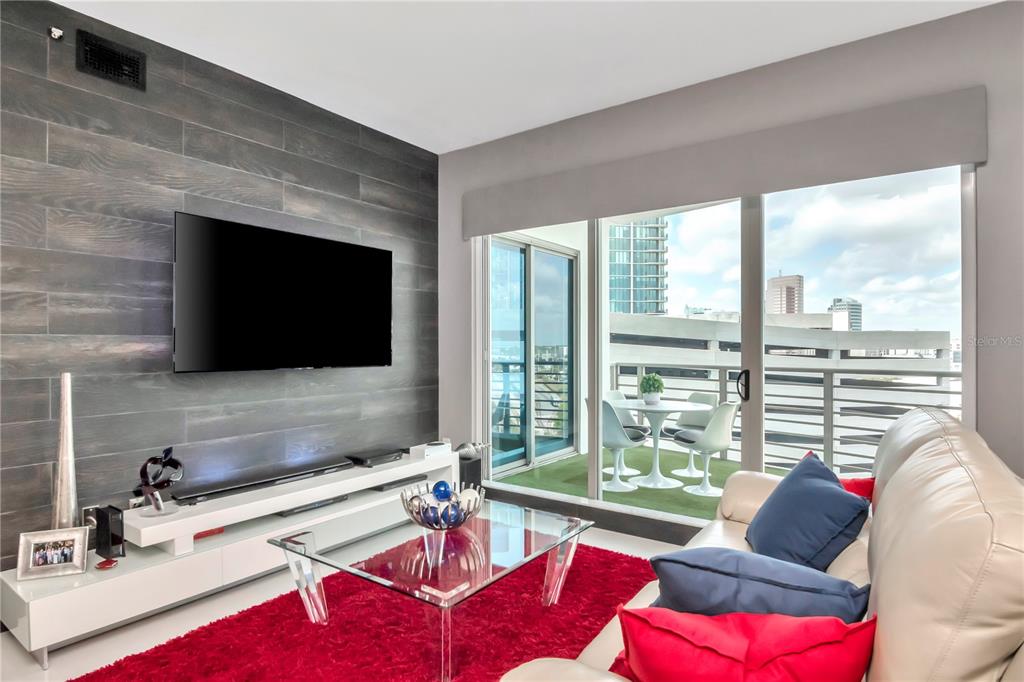 A living room features a wood-paneled accent wall, a red rug, and a balcony view — 449 S 12TH STREET UNIT 1006, TAMPA, FL