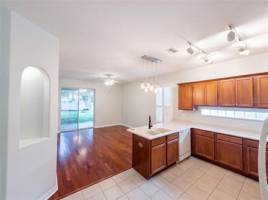 A kitchen with wood cabinets and tile flooring opens into a living area with hardwood floors — 33450 IRONGATE DRIVE, LEESBURG, FL