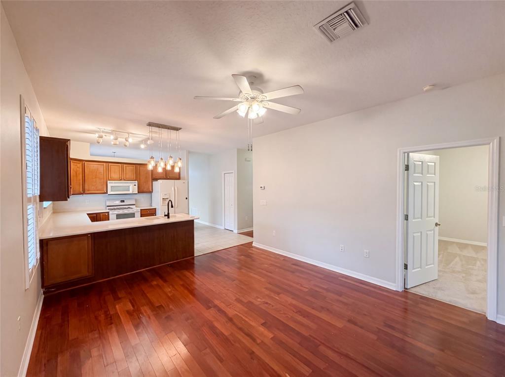 A kitchen with wood cabinets and a breakfast bar opens into a living area — 33450 IRONGATE DRIVE, LEESBURG, FL