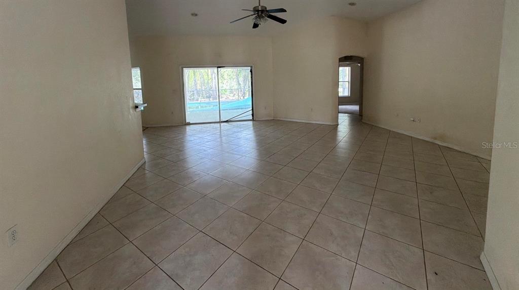 An open-concept foyer and living area with beige tile flooring and a white front door — 1365 BLAISDELL STREET, PORT CHARLOTTE, FL