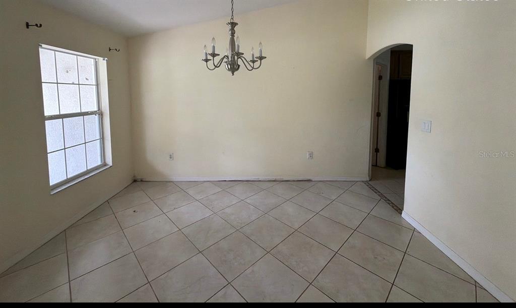 A kitchen with wood cabinets, dark countertops, tile flooring, and a breakfast bar — 1365 BLAISDELL STREET, PORT CHARLOTTE, FL