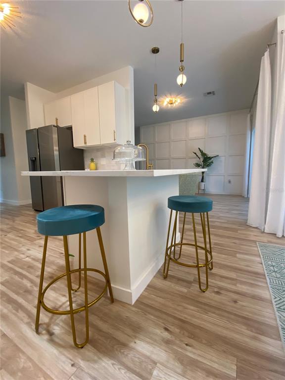 A kitchen island with two teal bar stools sits in front of white cabinets — 176 CAPE FLORIDA DRIVE, KISSIMMEE, FL