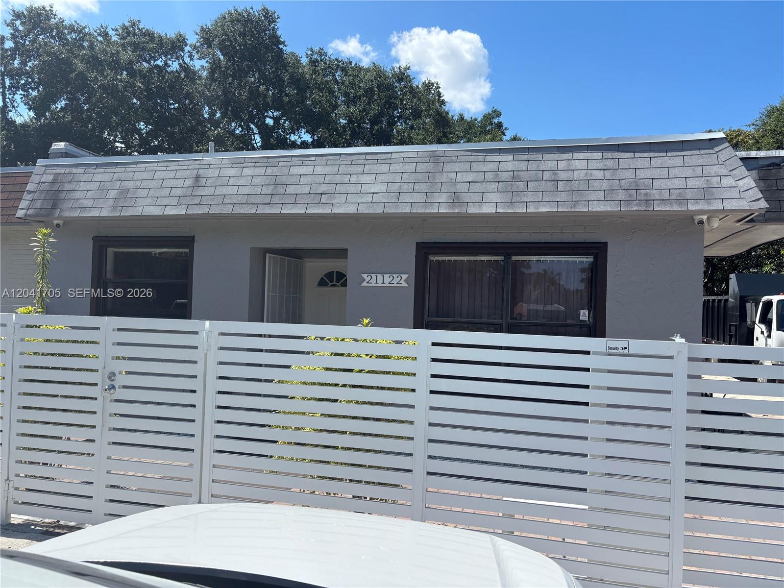 A single-story house with a gray exterior and a white horizontal slat fence — 21122 NW 39th Ave, Miami Gardens FL 33055, MIAMI GARDENS, FL