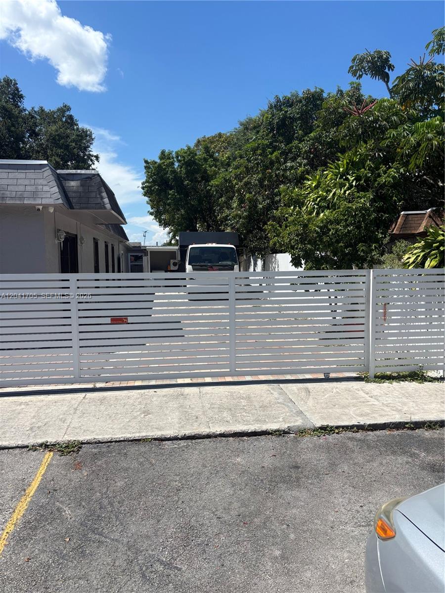 A white horizontal slat gate secures the entrance to a paved driveway and property — 21122 NW 39th Ave, Miami Gardens FL 33055, MIAMI GARDENS, FL
