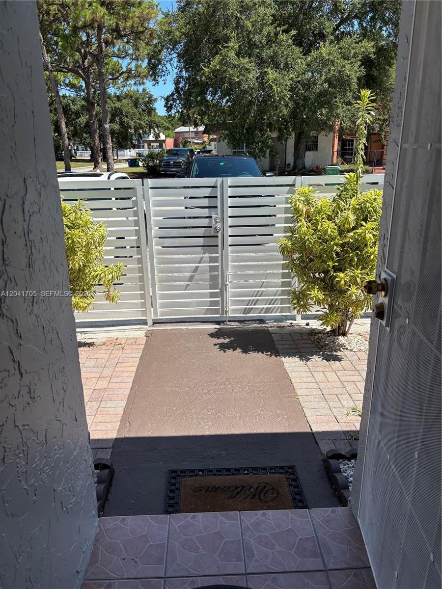 A view from a doorway looking out at a paved walkway and a metal gate — 21122 NW 39th Ave, Miami Gardens FL 33055, MIAMI GARDENS, FL