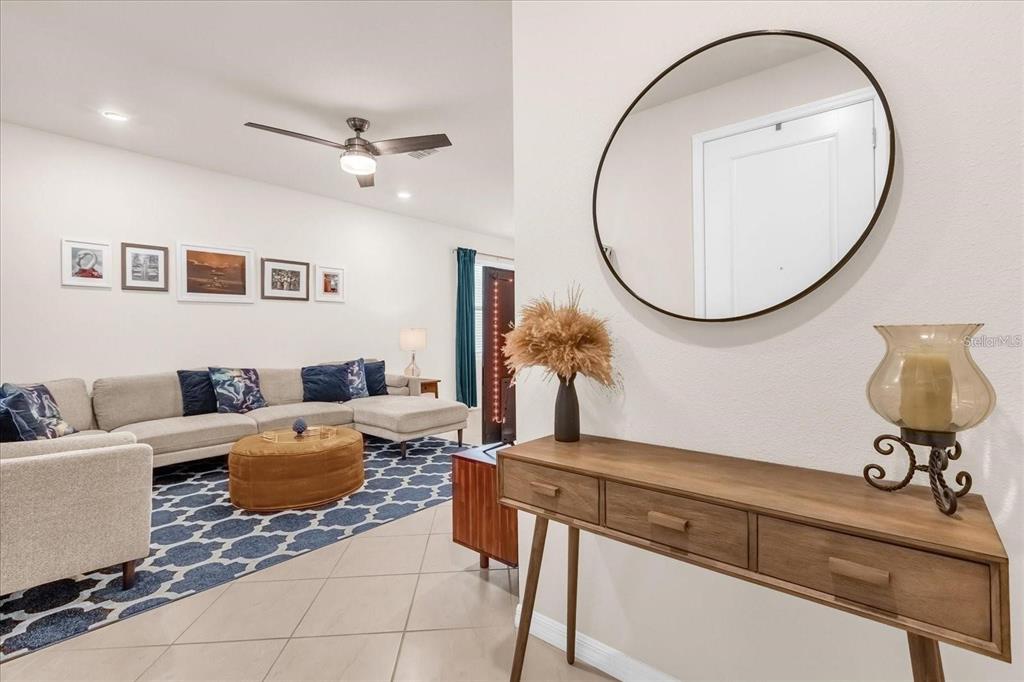 A living room features a sectional sofa, a patterned rug, and a wooden console table — 5090 CASPIAN STREET, ST CLOUD, FL