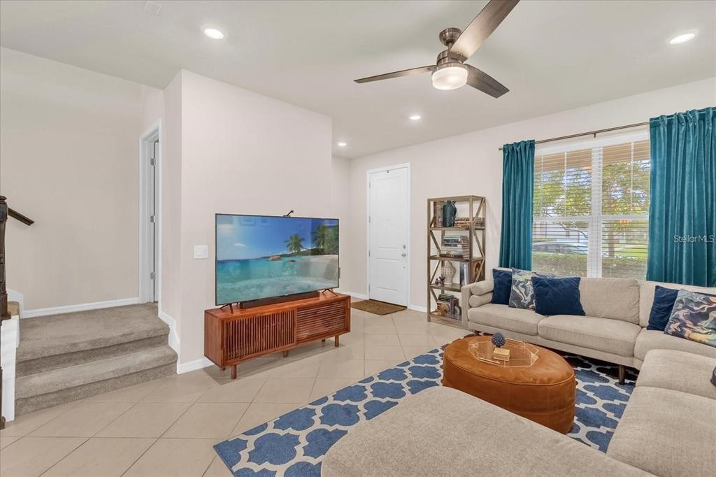 A living room features a sectional sofa, a television on a wooden console, and stairs — 5090 CASPIAN STREET, ST CLOUD, FL